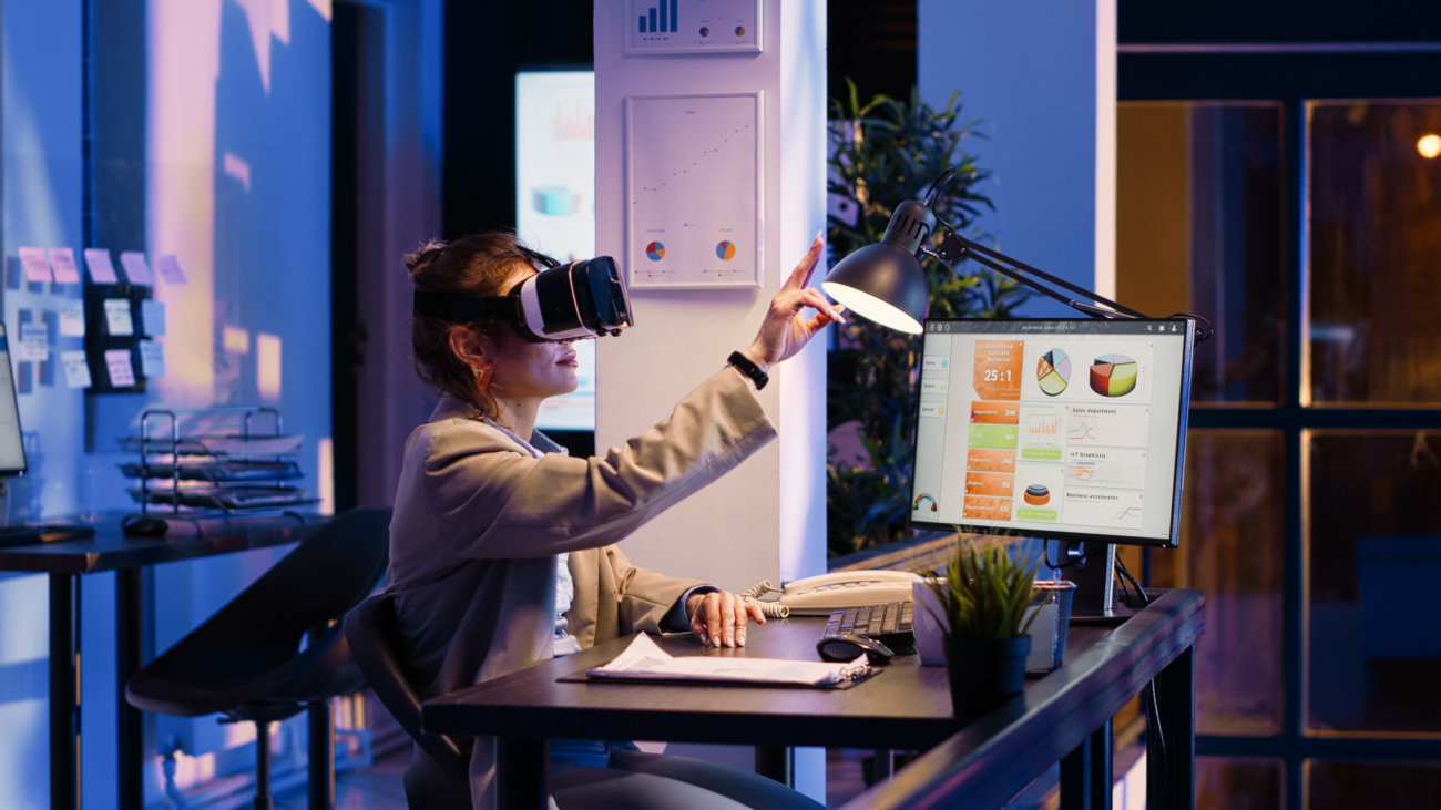 Young businesswoman working with vr glasses at night, working overtime on economy development in office. Female manager using virtual reality headset, planning financial diagrams report on pc.